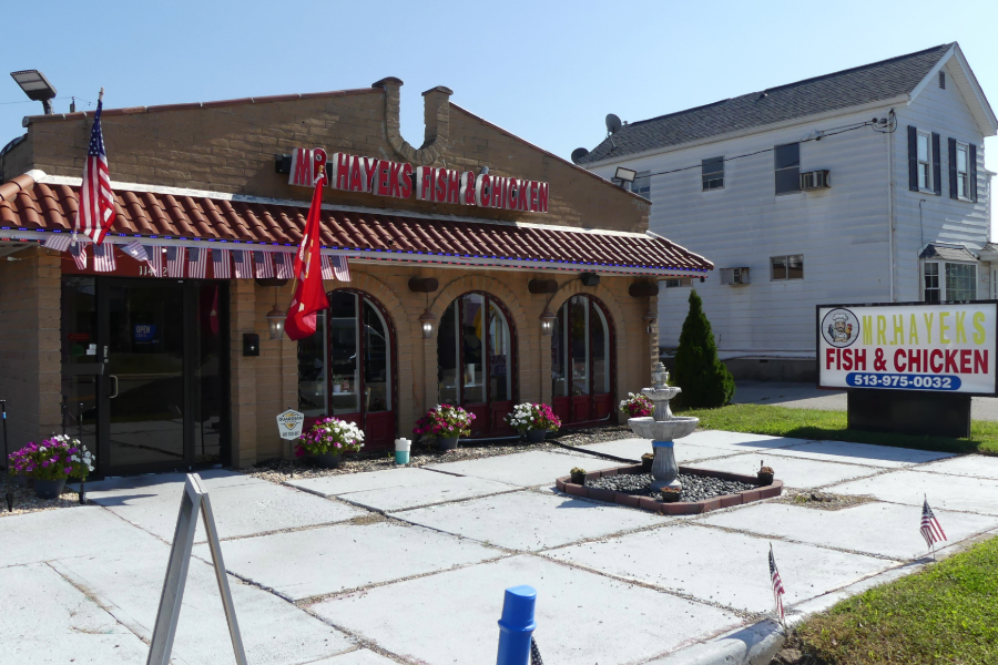 Street view of Mr. Hayek's Fish & Chicken: tan brick building with a red tile roof, striped awning and a roadside sign on Springfield Pike